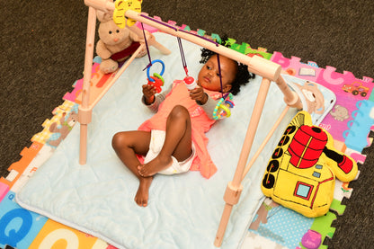 Wooden baby gym for infants, promoting motor skills and hand-eye coordination.