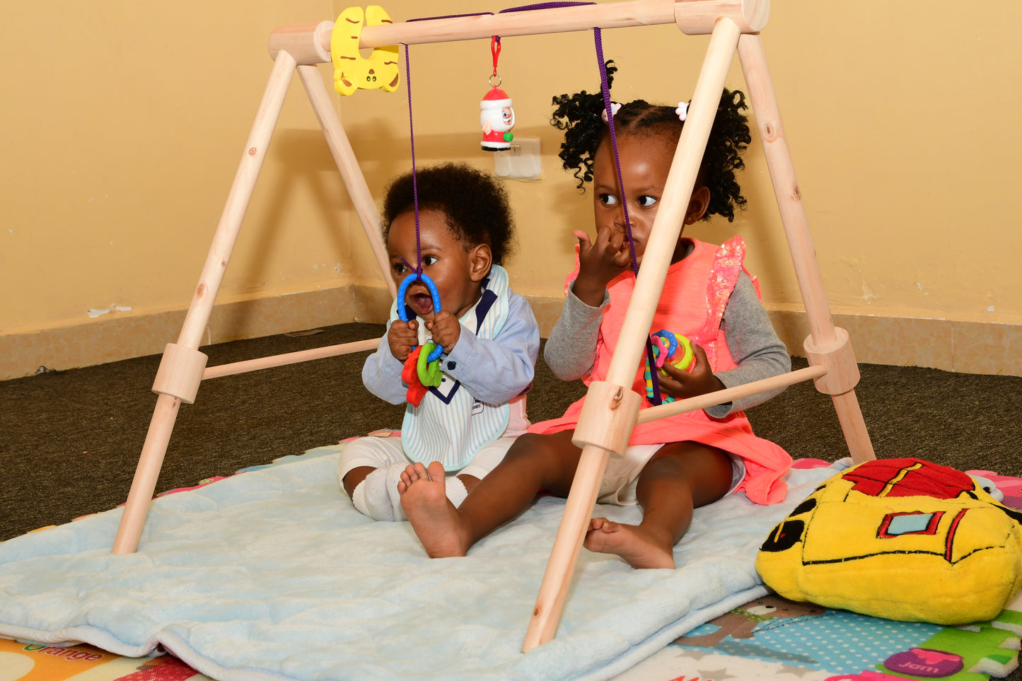 Wooden baby gym for infants, promoting motor skills and hand-eye coordination.