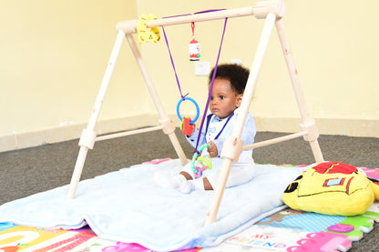 Wooden baby gym for infants, promoting motor skills and hand-eye coordination.