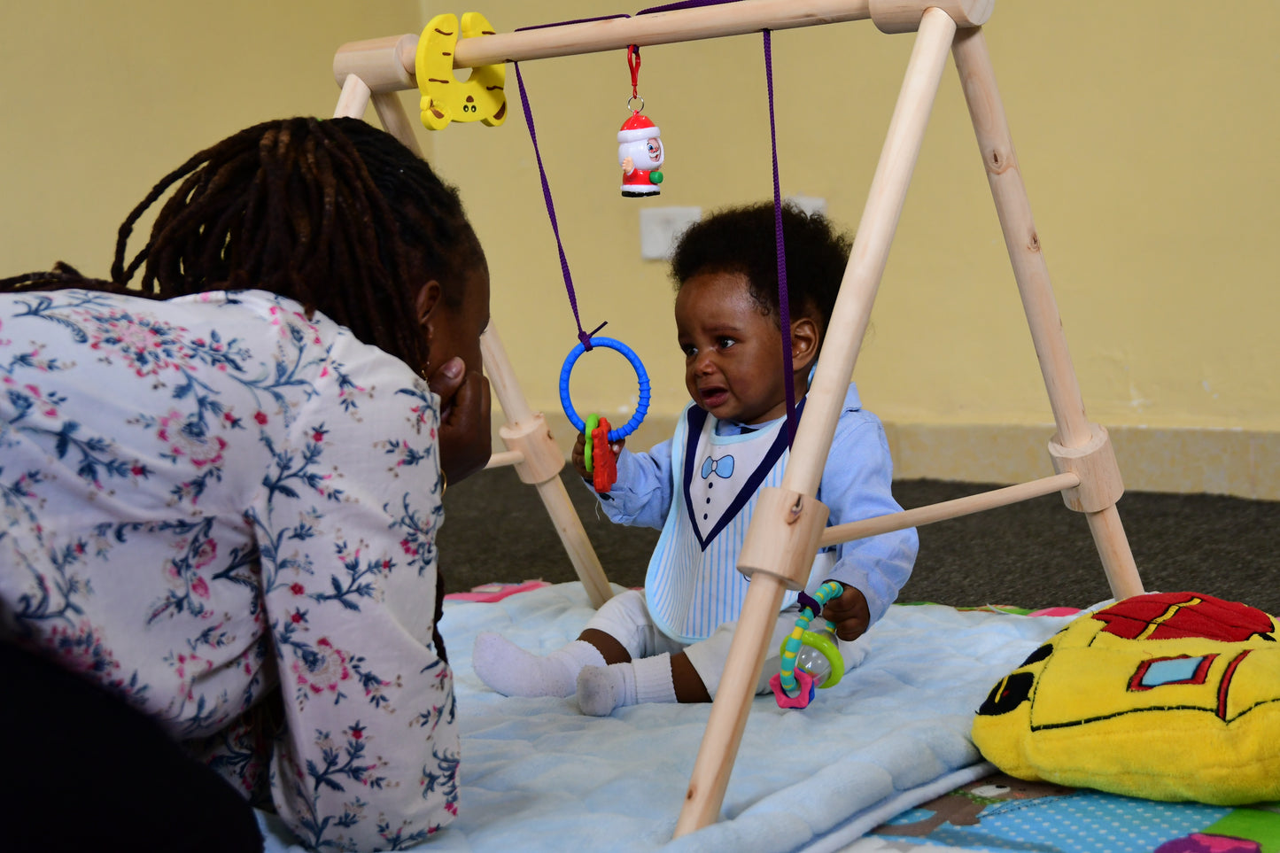 Wooden baby gym for infants, promoting motor skills and hand-eye coordination.