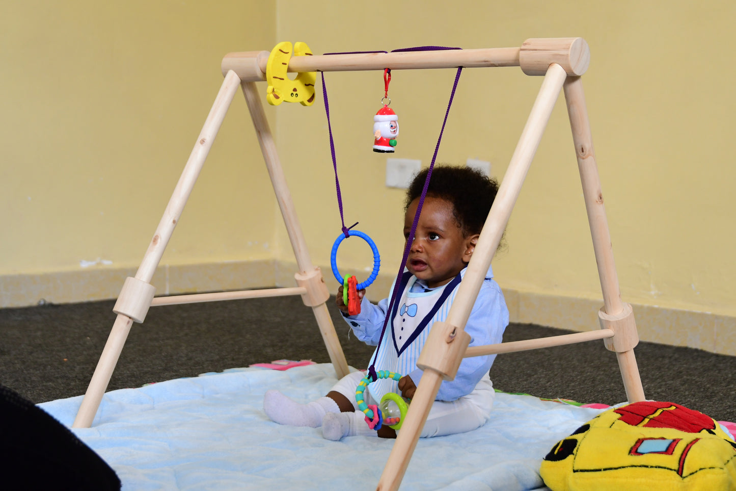 Wooden baby gym for infants, promoting motor skills and hand-eye coordination.